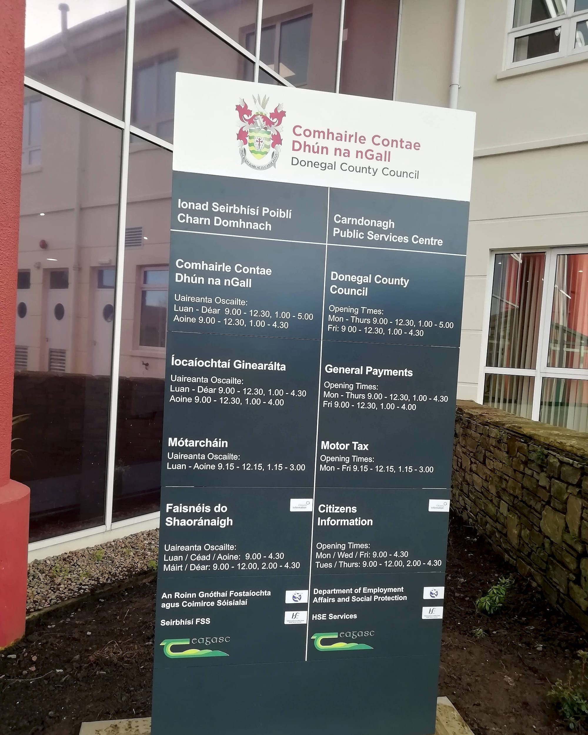Bilingual Irish and English external totem at a Donegal County Council public services centre, Irish in the left column and English in the right at matching size