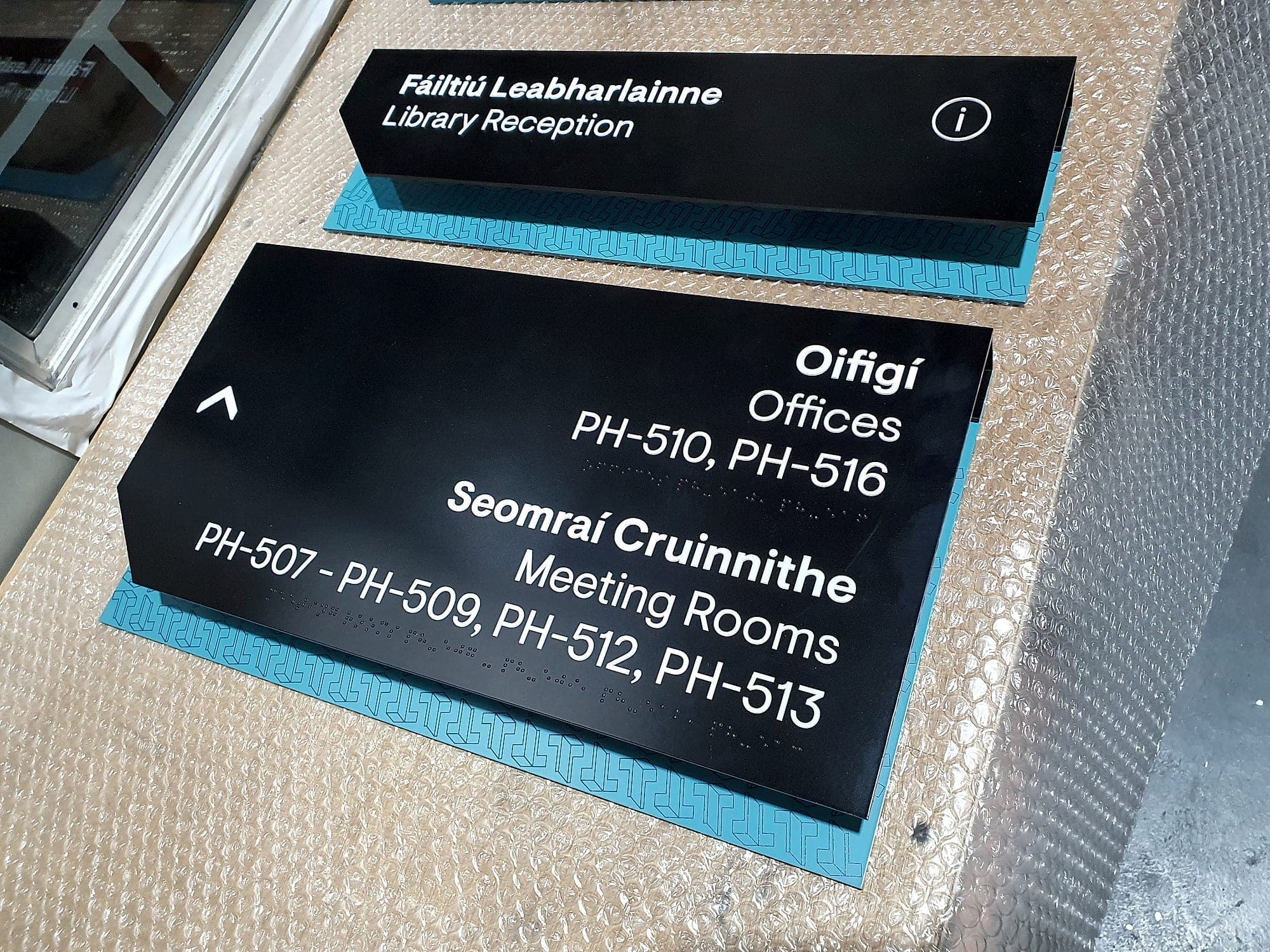 Bilingual Irish and English directional sign panels for Park House at TU Dublin, with room codes and braille, finished and laid out before installation, the output of signage design automation