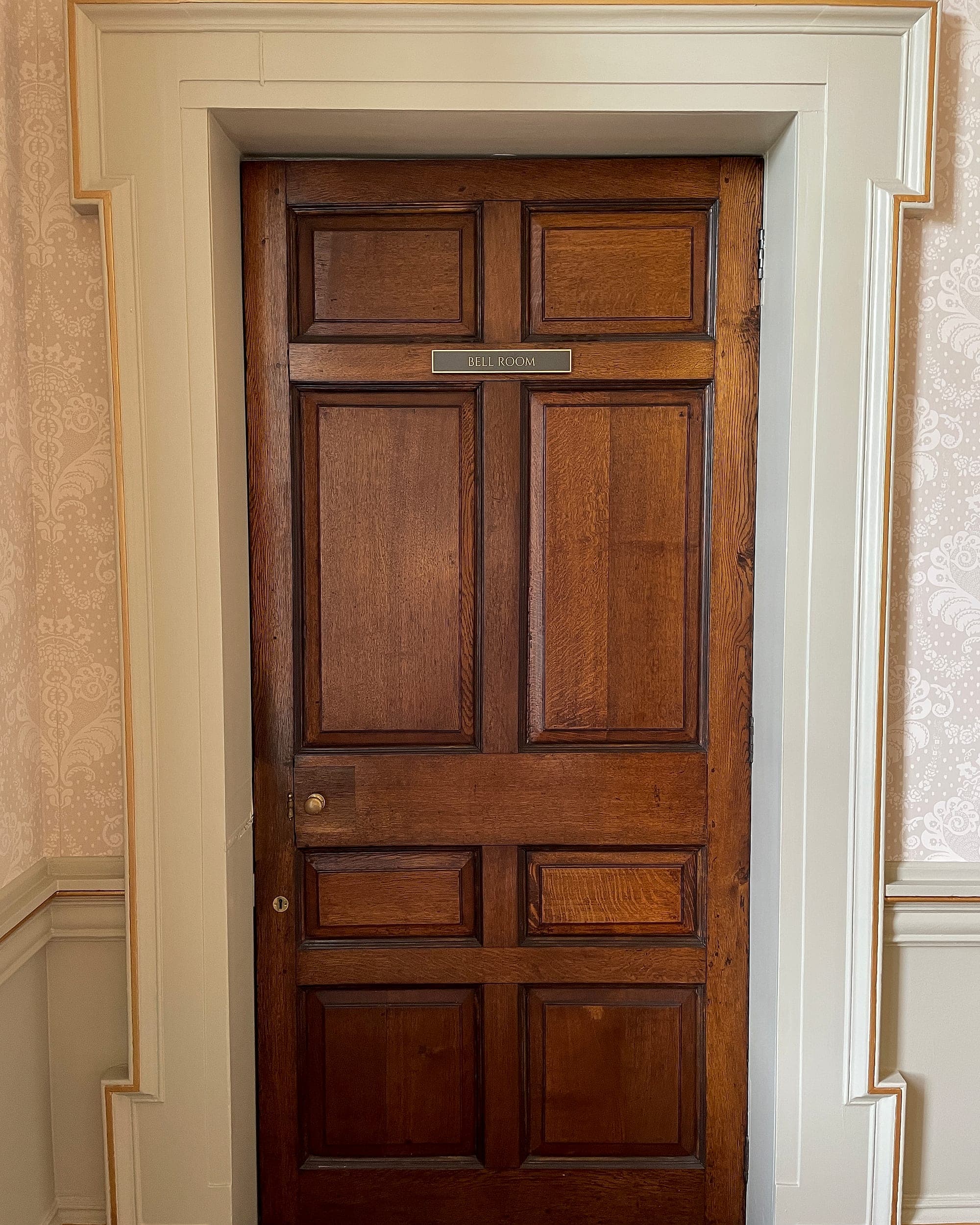 Engraved brass room nameplate reading Bell Room, fixed to an oak panelled door in a heritage interior at Carton House