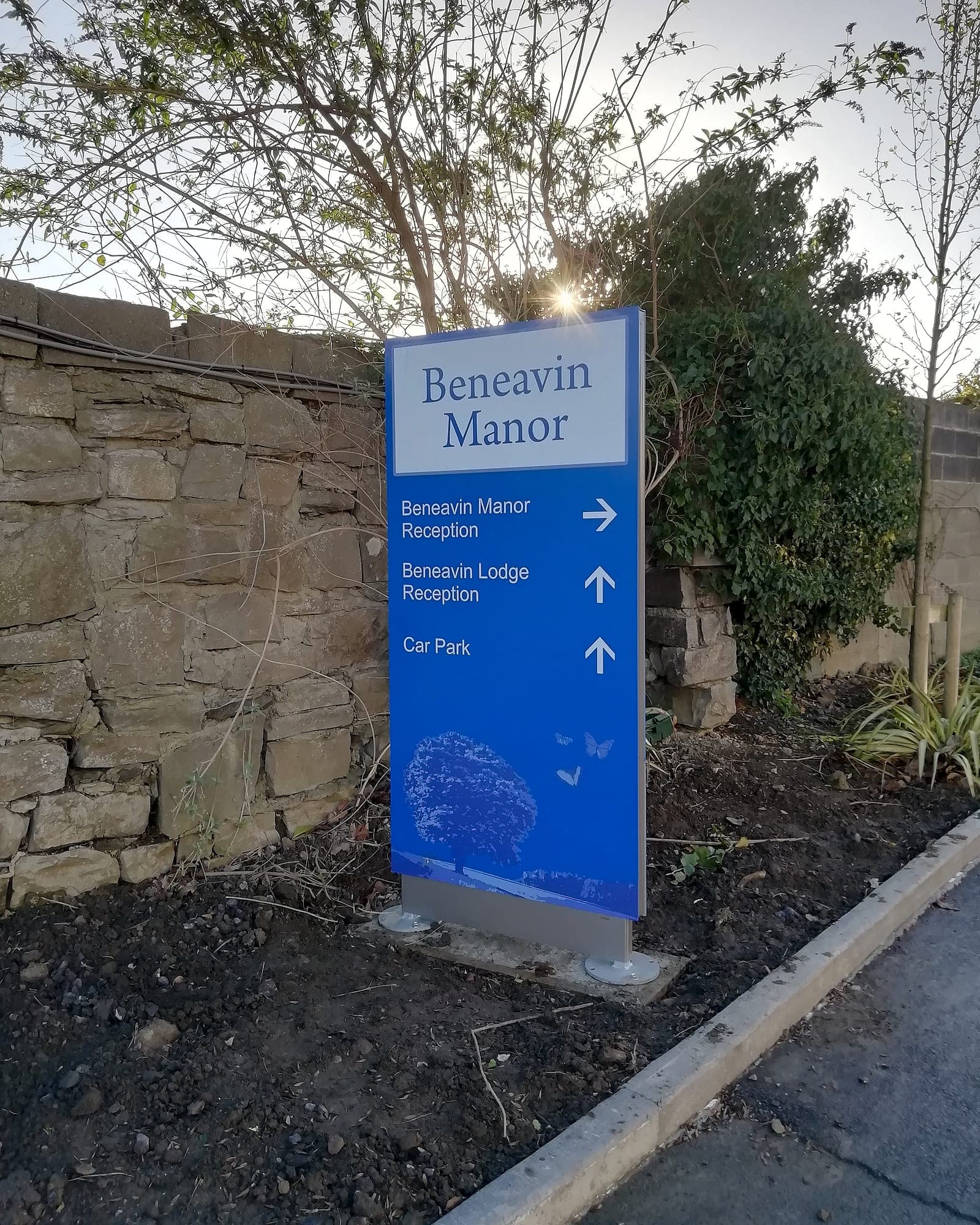 Beneavin Manor estate arrival totem beside a stone boundary wall, directing drivers to two separate receptions and a car park