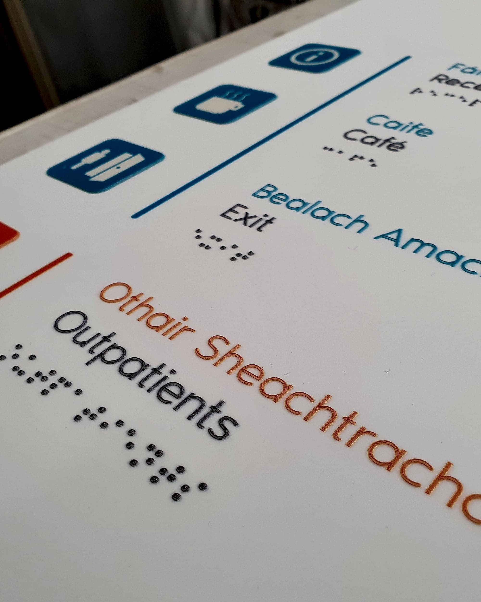 The Rotunda Hospital (BS 8300 compliant signage detail): bilingual tactile wayfinding panel with raised mixed-case lettering, tactile pictograms and braille beneath each line