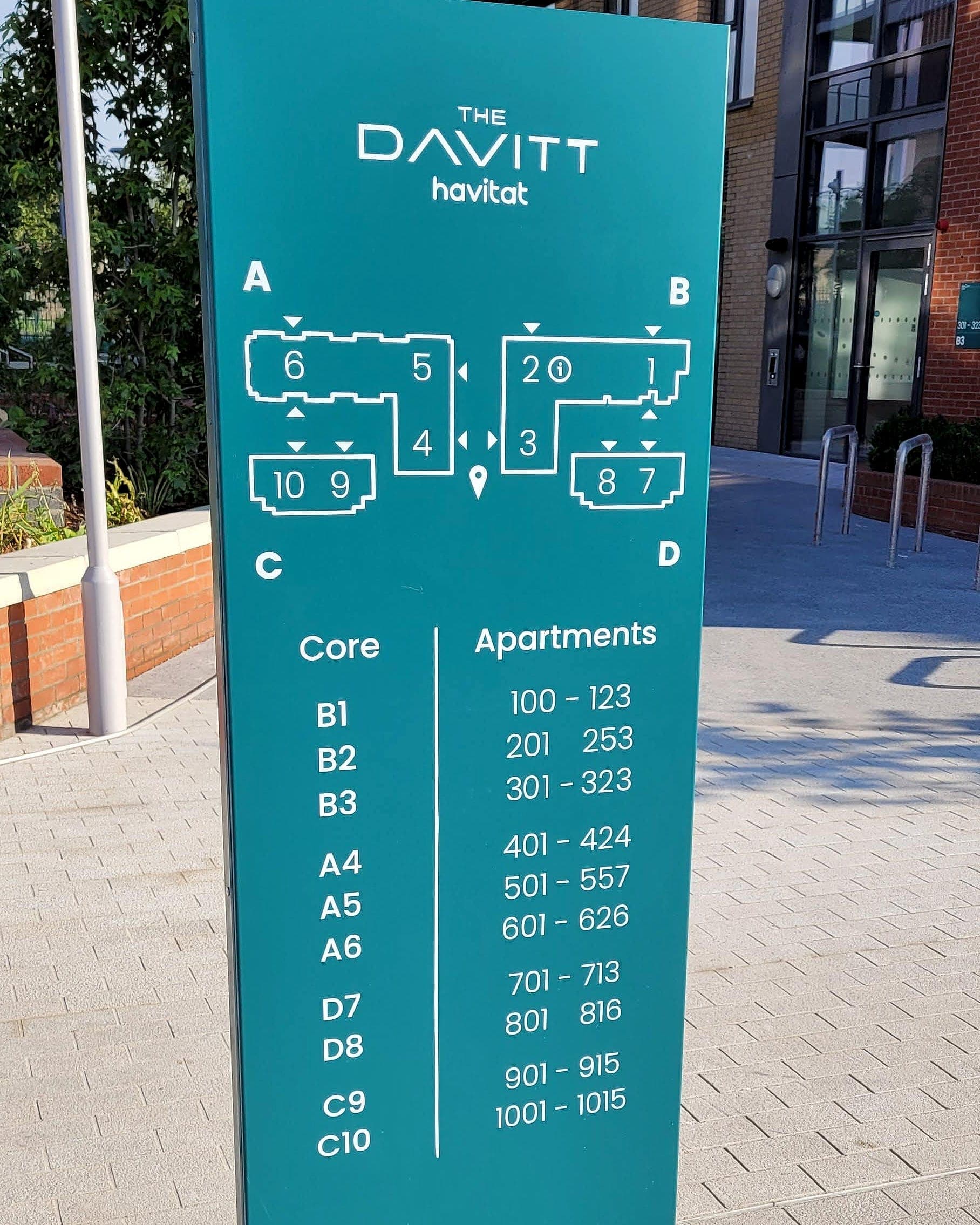 Site orientation totem at Davitt House: teal external totem with a plan diagram of blocks A to D and a Core / Apartments table listing cores B1 to C10 against apartment number ranges