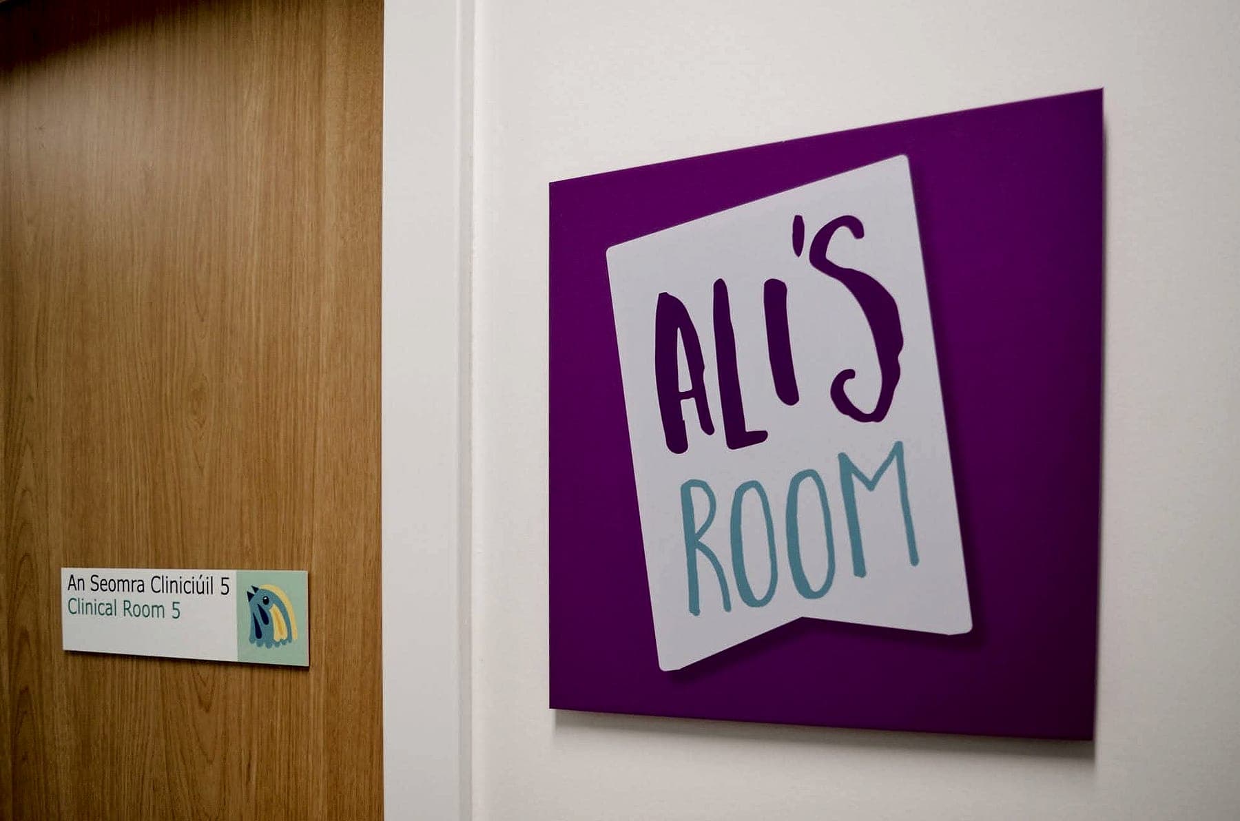 Bilingual Irish and English room signage at Temple Street Children's Hospital beside a colourful named-room supergraphic