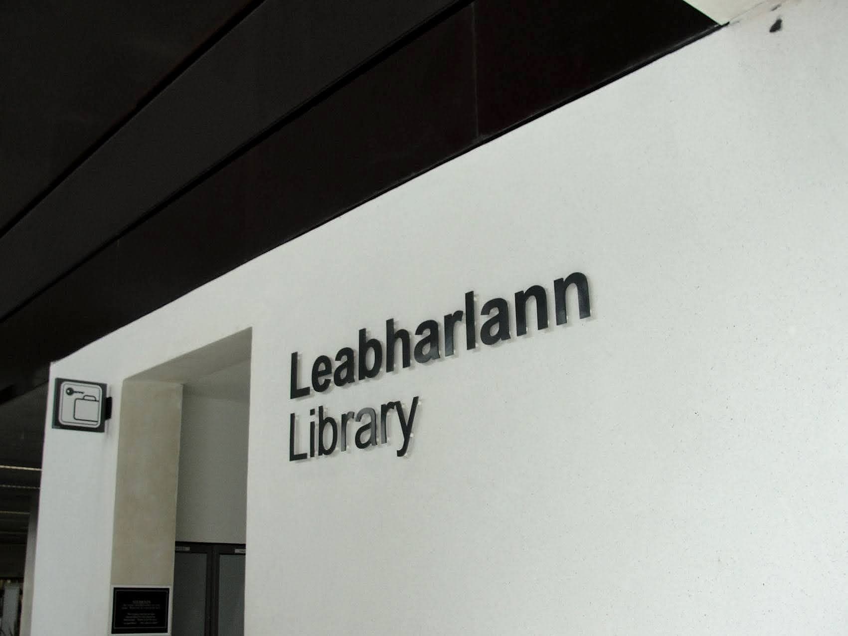 Bilingual Leabharlann / Library cut lettering above a public library entrance with a book pictogram projecting from the adjacent wall