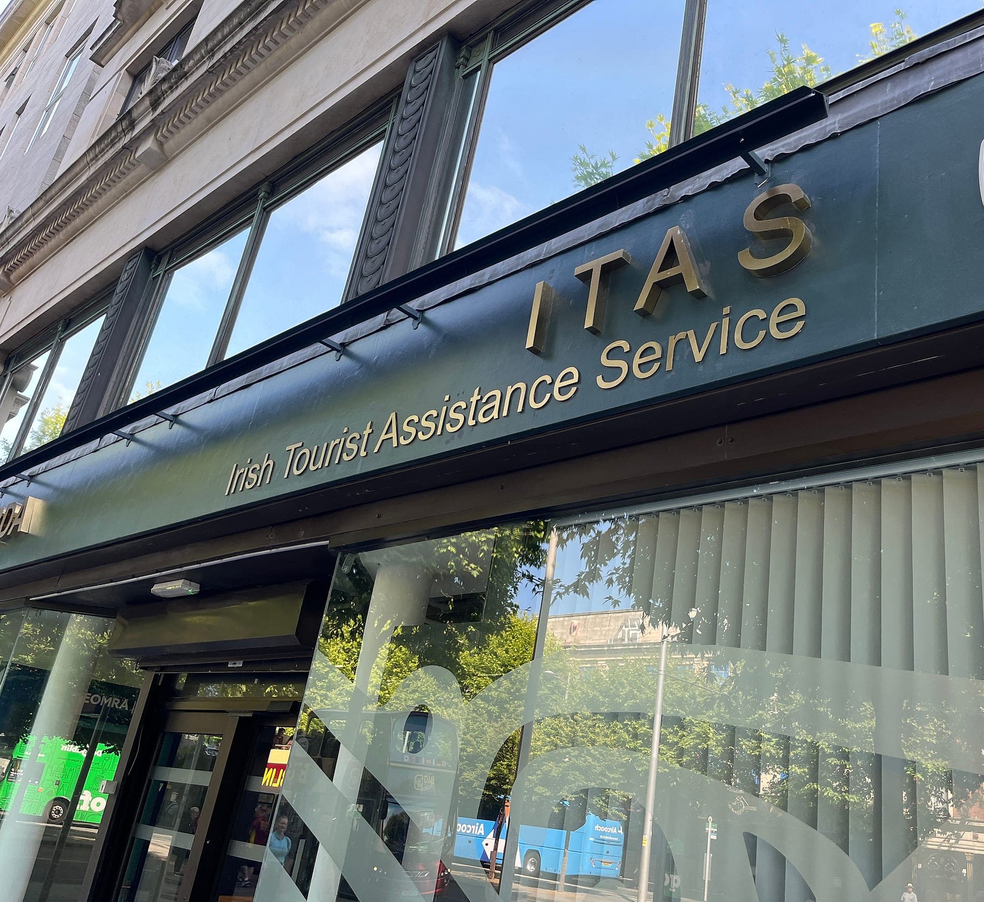 Solid brass-coloured built-up letters on the dark green painted fascia of the An Garda Síochána station on O'Connell Street, with etched-effect window film graphics on the glass below