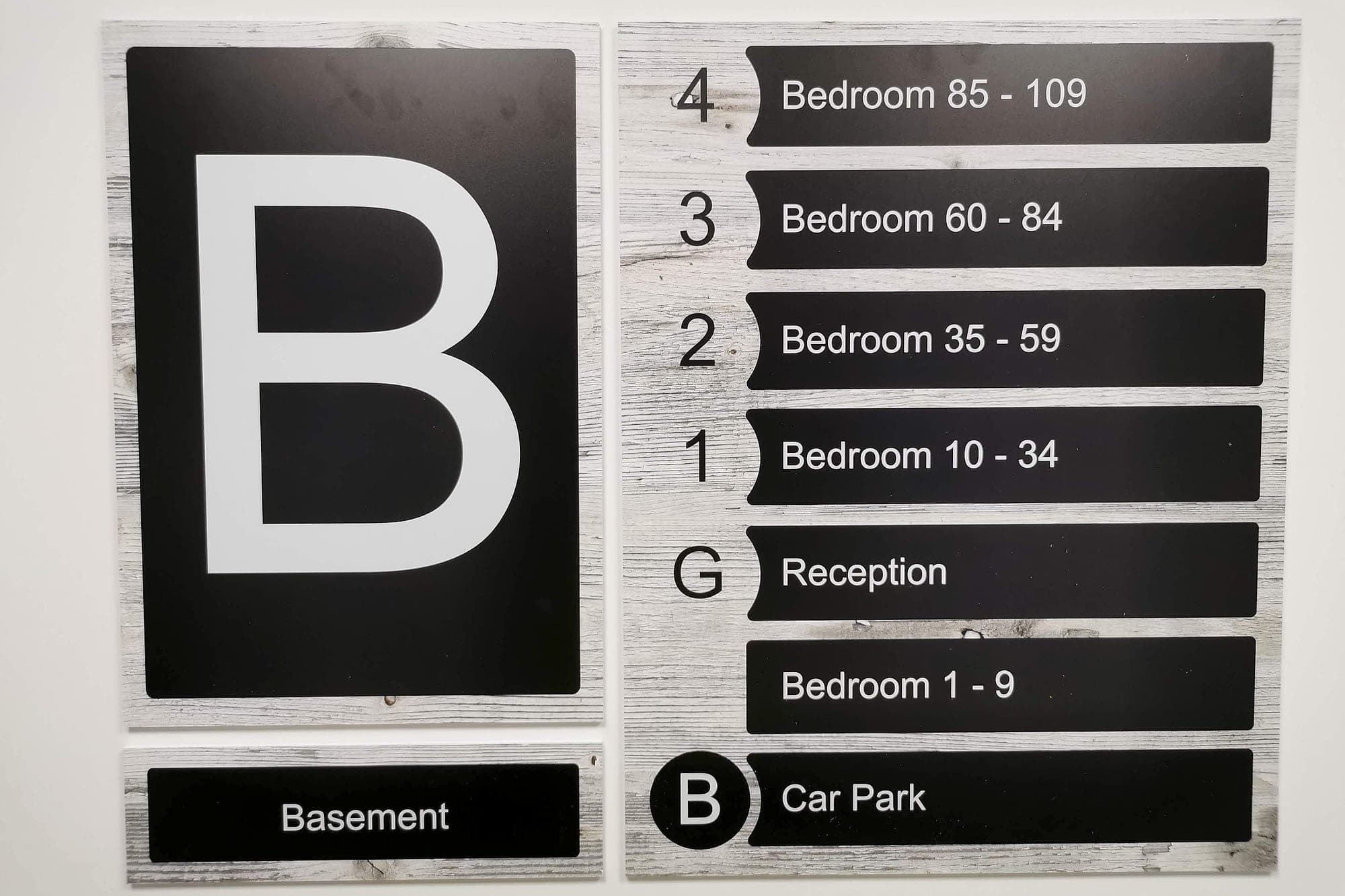 Level identification and floor directory in a care home: a large letter B beside a list of bedroom ranges, reception and car park, sized for elderly readers to take in from a distance