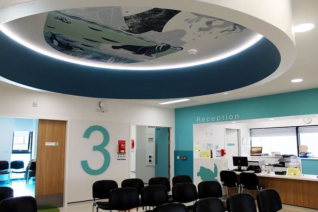 Colour used as a wayfinding landmark at Temple Street Children's Hospital: teal supergraphic numeral three and teal reception wall beneath a circular ceiling mural