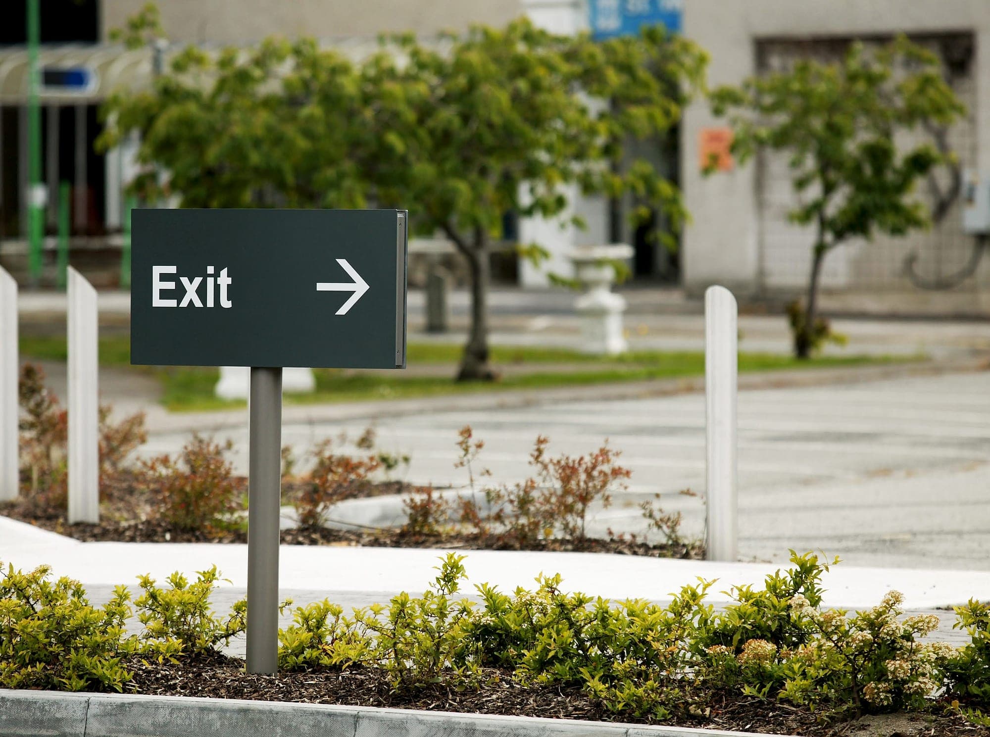 St Vincent's Private Hospital: external post-mounted directional sign reading Exit with an arrow in a landscaped car park, a wayfinding sign rather than a statutory fire exit sign