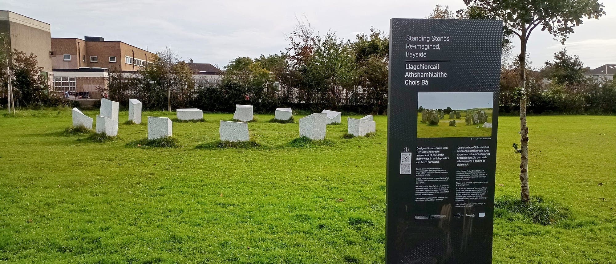 Durable external signage in the public realm: bilingual Irish and English interpretation totem for Fingal County Council beside a re-imagined standing stone circle in open parkland at Bayside, Dublin