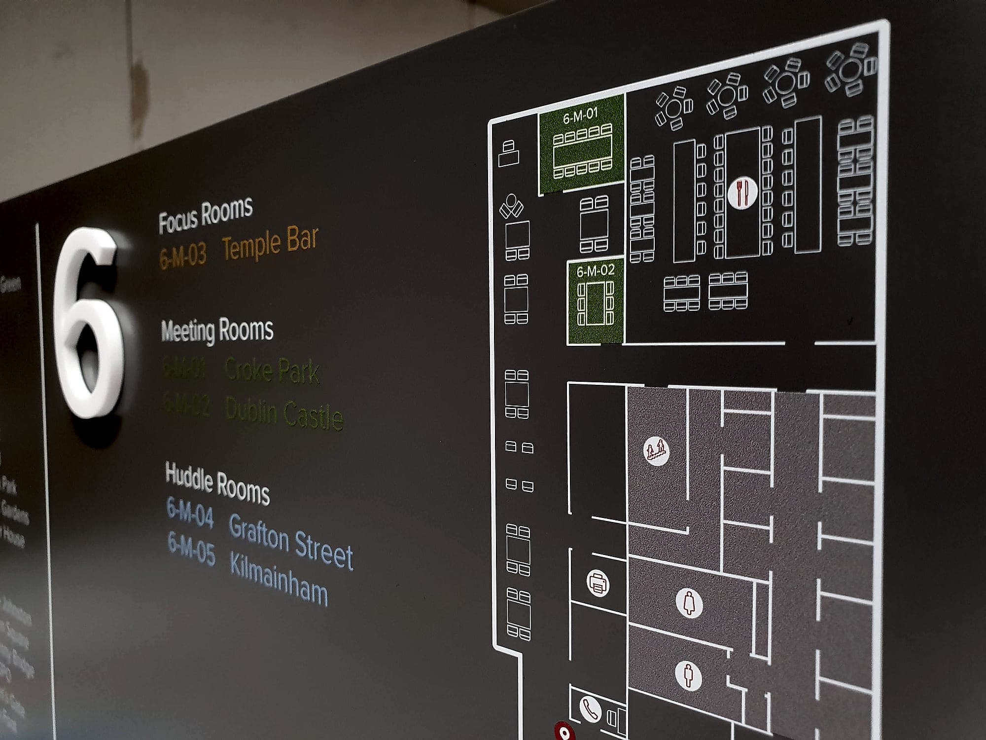 Gilead: detail of a floor-plan wayfinding panel showing a level plan with room codes, layouts and red pictograms for stairs, toilets and facilities