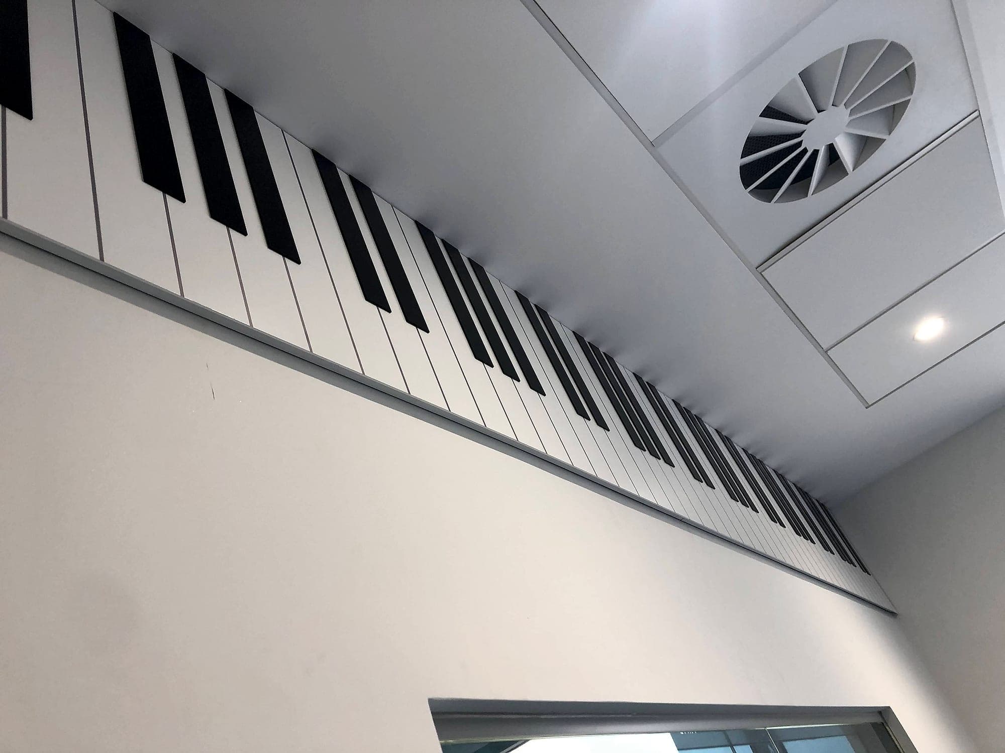 The National Rehabilitation Hospital: environmental graphic of a piano keyboard running the full length of a bulkhead above a doorway, in black and white against a white interior