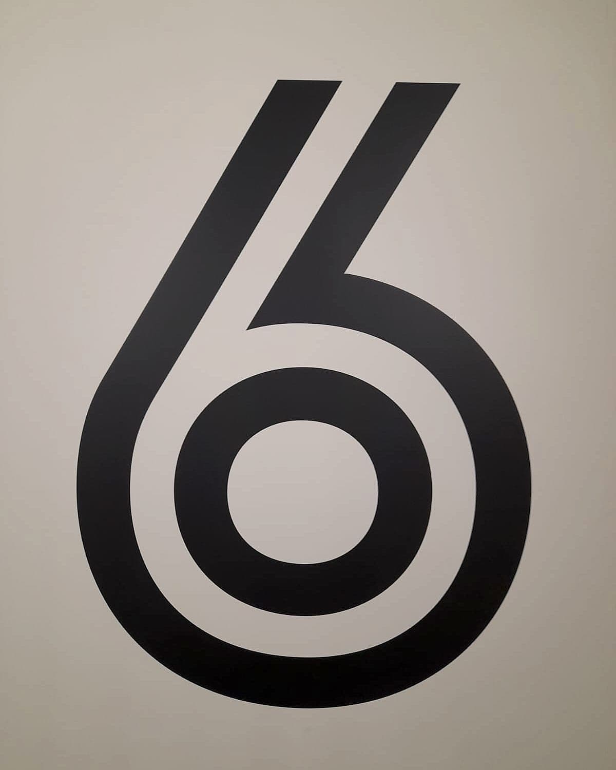 Oversized level numeral supergraphic at Marshal's Yard, East Road: a six in cut vinyl applied at full wall height in a residential lift lobby to identify the floor