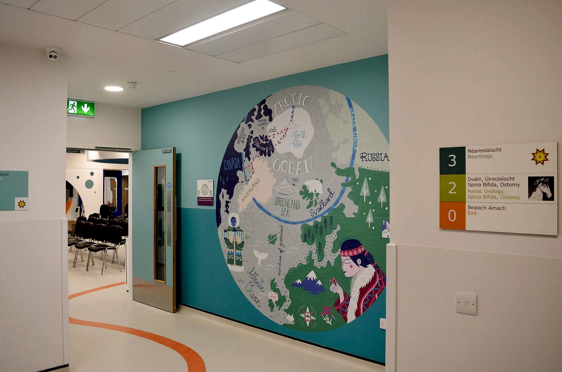A circular Arctic map wall graphic beside a colour-coded bilingual level directory at Temple Street Children's Hospital, with a route line set into the floor